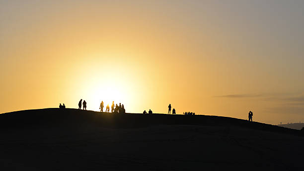 Maspalomas, Gran Canaria, Spain - 5 September 2024: People watching a colorful sunset at a Maspalomas dune, Gran Canaria island