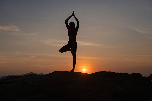 Silhouette of sport woman striking a graceful yoga pose against the glowing. This image perfectly represents the essence of meditation, wellness, and the pursuit of balance in life. Silhouette of sport woman striking a graceful yoga pose against the glowing. This image perfectly represents the essence of meditation, wellness, and the pursuit of balance in life. yoga stock pictures, royalty-free photos & images