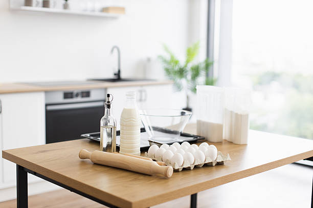 istock Cooking ingredients arranged on wooden kitchen table with bright background view 2207797202