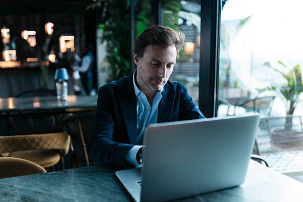 istock Businessman working on laptop in a cafe, focused on his tasks 2207799301