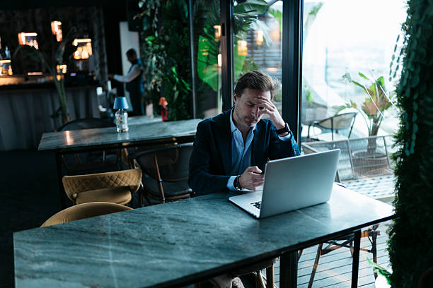 istock Businessman having headache while working on laptop in a cafe 2207799303