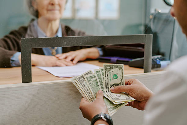 istock Senior Bank Clerk Assisting Customer with Financial Transaction 2207800707