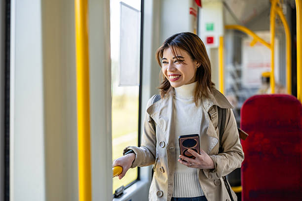 istock Smiling young woman using mobile phone in a public transport 2207802731