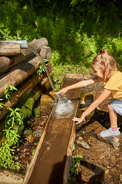 istock Child refreshing face at natural spring during sunny day in peaceful forest setting 2207803406