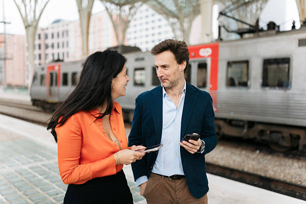 istock Businesspeople talking on train platform holding smartphones 2207803490