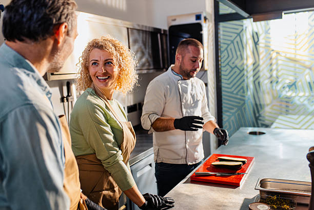 istock Couple enjoying a cooking class with a chef preparing eggplant for a meal in the kitchen. 2207803551