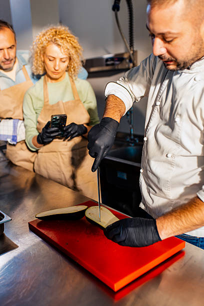 istock Couple enjoying a cooking class with a chef preparing eggplant for a meal in the kitchen. 2207803566