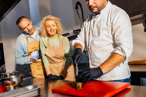 istock Couple enjoying a cooking class with a chef preparing eggplant for a meal in the kitchen. 2207803574