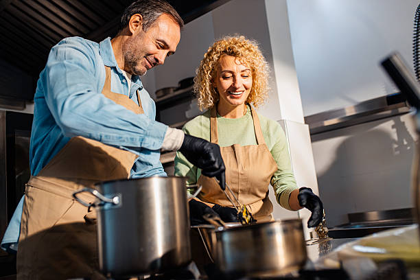 istock Couple enjoying a cooking class with a chef preparing meal in the kitchen. 2207803582