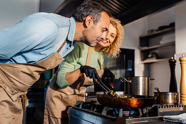 istock Couple enjoying a cooking class with a chef preparing meal in the kitchen. 2207803589