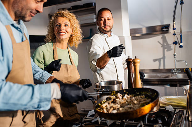 istock Couple enjoying a cooking class with a chef preparing meal in the kitchen. 2207803597