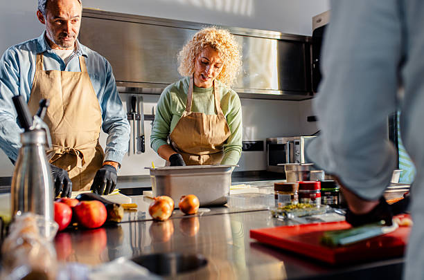 istock Couple enjoying a cooking class with a chef preparing meal in the kitchen. 2207803622