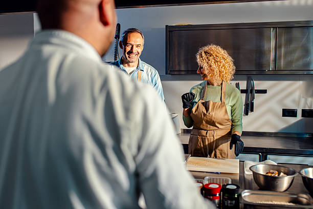 istock Middle-aged couple enjoying a cooking class with a chef preparing meal in the kitchen. 2207803706