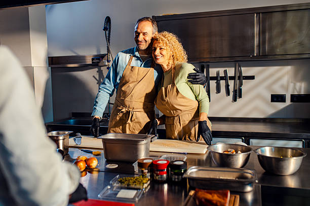 istock Middle-aged couple enjoying a cooking class with a chef preparing meal in the kitchen. 2207803707