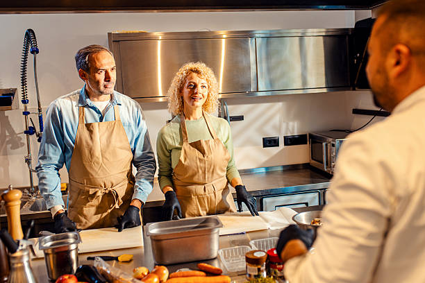 istock Middle-aged couple enjoying a cooking class with a chef preparing meal in the kitchen. 2207803715