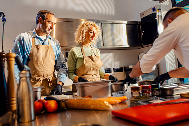 istock Middle-aged couple enjoying a cooking class with a chef preparing meal in the kitchen. 2207803731