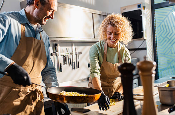 istock Couple enjoying a cooking class with a chef preparing meal in the kitchen. 2207803735