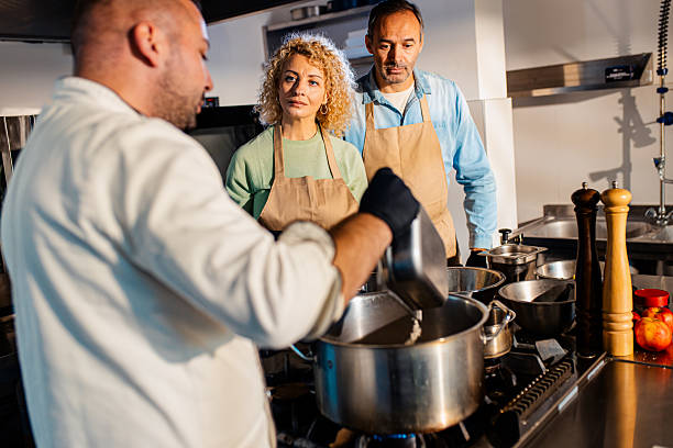 istock Couple enjoying a cooking class with a chef preparing meal in the kitchen. 2207803742