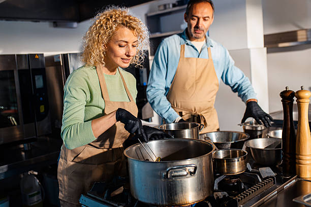 istock Couple enjoying a cooking class with a chef preparing meal in the kitchen. 2207803748