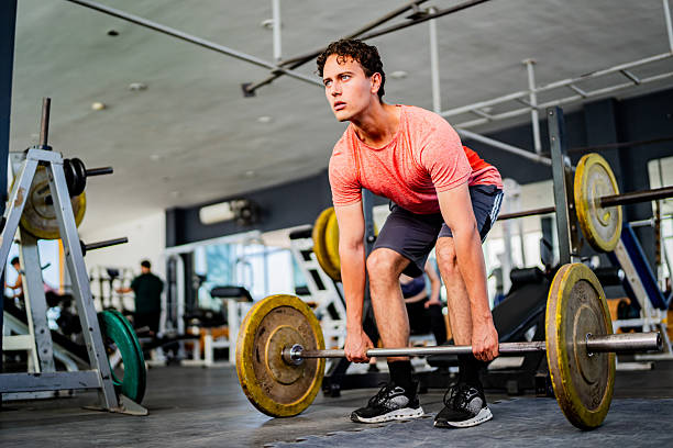 Young man doing deadlift exercise at gym