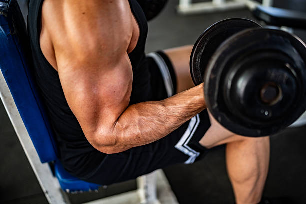 istock Close-up of man doing exercise using dumbbell at gym 2207803971