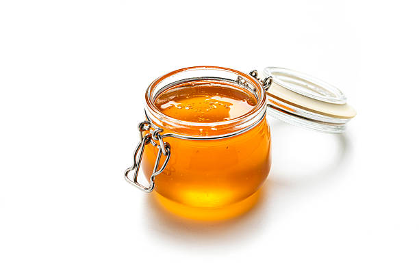 Open glass jar filled with organic honey  isolated on white background