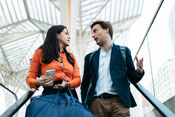 istock Businesspeople discussing while ascending on escalator in lisbon 2207804299