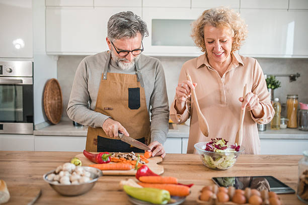 istock A cheerful man cuts vegetables on a cutting board while his wife makes a salad. The two are in the kitchen preparing a healthy meal together 2207805237