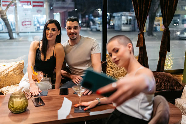 istock Three Young Friends Taking Selfies Using A Phone While Drinking Cocktails And Whiskey In A Bar At Night 2207806242