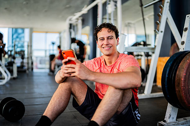 istock Portrait of young man using mobile phone at gym 2207806411