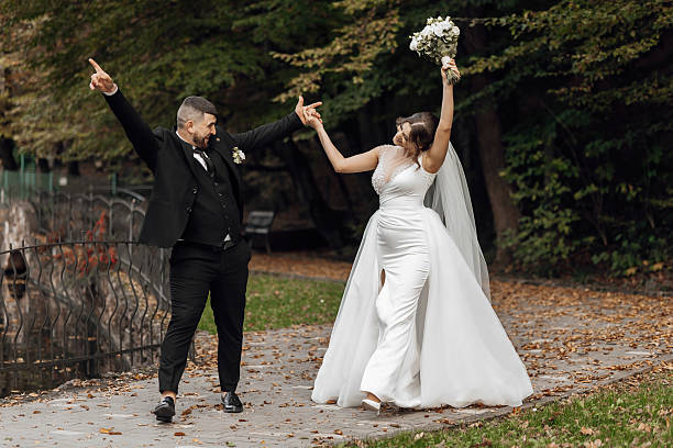 istock A bride and groom are walking down a path, the bride is holding a bouquet 2207806667