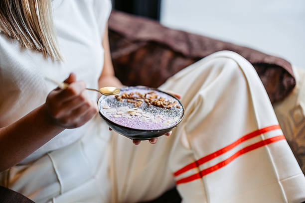 Young Woman Eating An Acai Bowl In A Café Indoors Young woman eating an Acai bowl in a café indoors. Close-up. eating chia seeds stock pictures, royalty-free photos & images