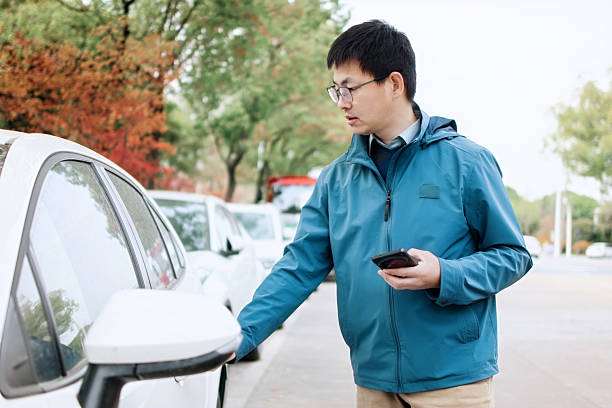 istock asian man using smart phone  open door of car 2207808632