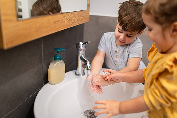 istock Siblings washing their hands with liquid soap and water in modern home bathroom, learning independence and good hygiene 2207810252