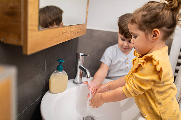 istock Siblings washing their hands with liquid soap and water in modern home bathroom, learning independence and good hygiene 2207810292