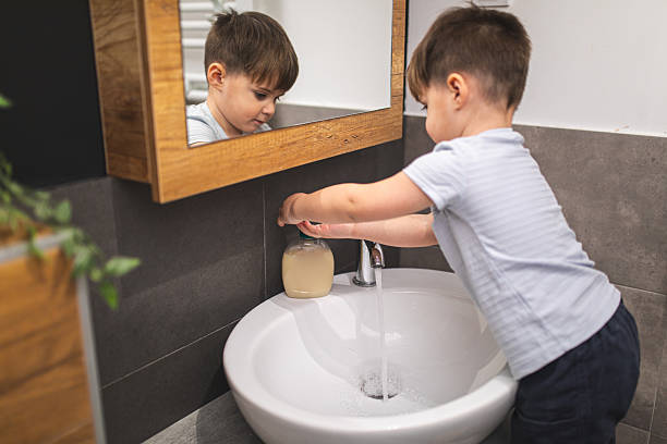 istock Smiling little boy preparing to wash his hands with liquid soap and water in modern home bathroom 2207810607