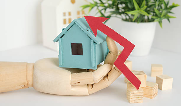istock A hand holding a blue house with a red arrow pointing upwards 2207810978