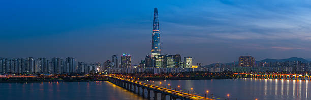 Panoramic view across the Han River to the futuristic highrise cityscape of the Jamsil district of central Seoul, South Korea’s vibrant capital city at sunset.