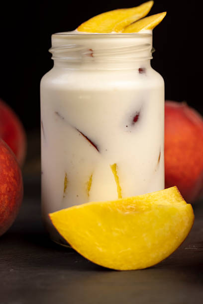 yogurt and peaches cut into pieces on slate, fermented milk product with peach flavor with the addition of pieces of peach, closeup, side view