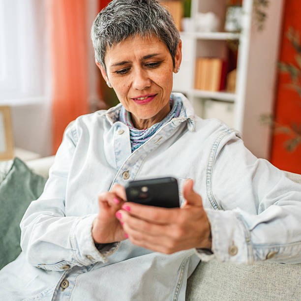 istock mature woman sit on sofa and use mobile phone at home 2207821713