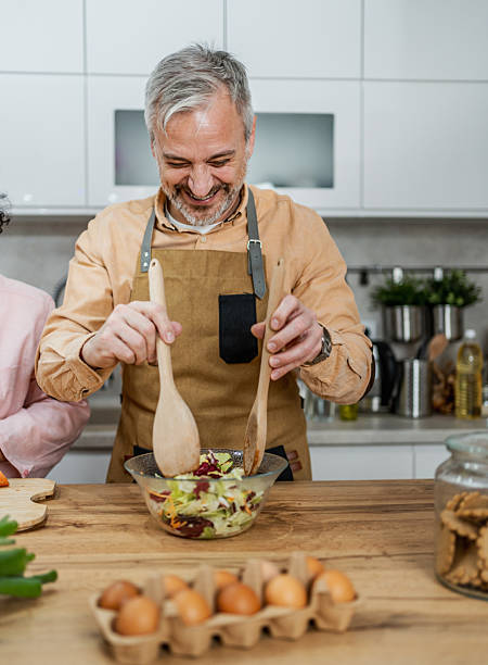istock Mature man making salad in the kitchen 2207823980