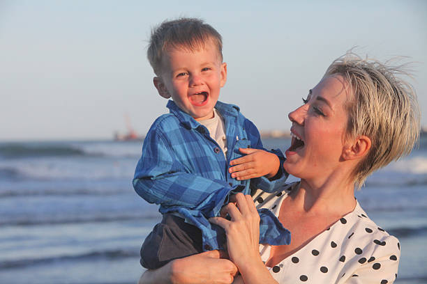 portrait of young happy  woman with her toddler son on the beach bonding