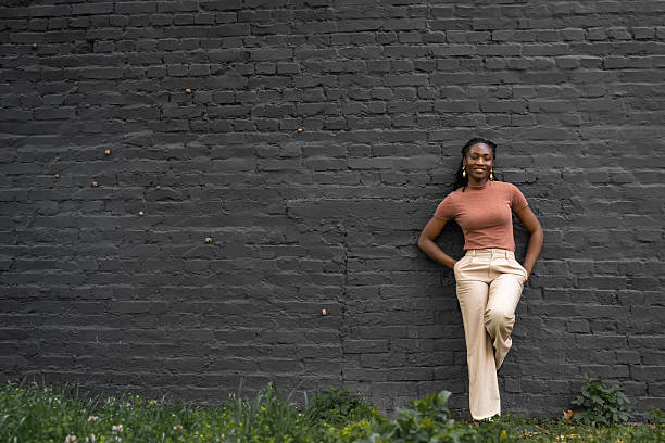 istock girl leaning against a large brick wall 2207826879