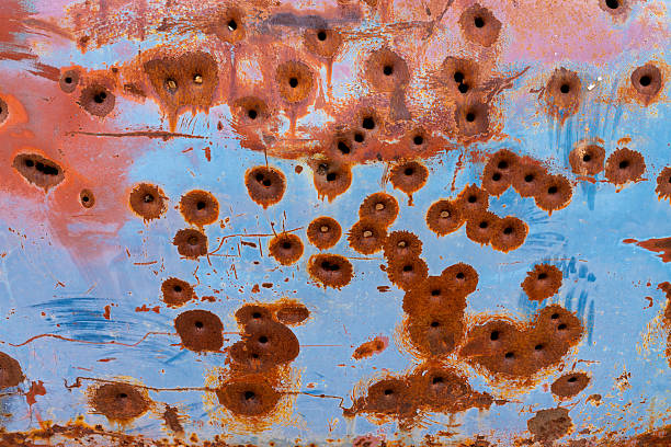 Old Rusty Car Detail with Bullet Holes - Textured background of blue painted metal, rust and bullet holes.
