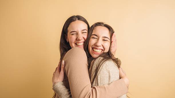 istock Two joyful friends embracing with laughter 2207830128