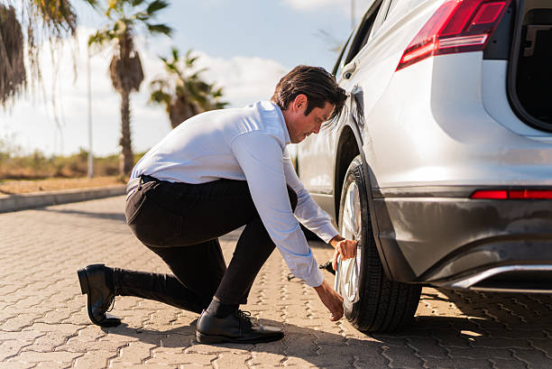 istock Mid adult man changing flat tire on the road 2207831461