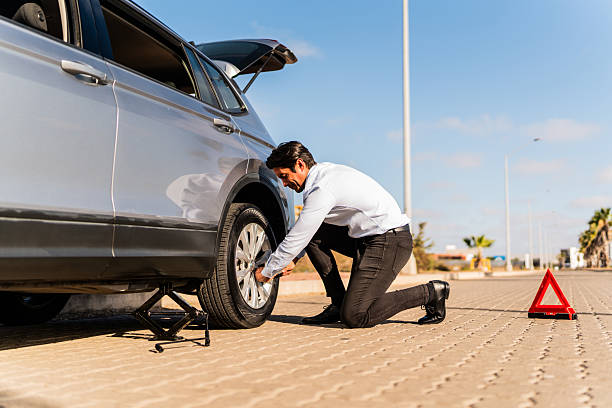 istock Mid adult man changing flat tire on the road 2207831464