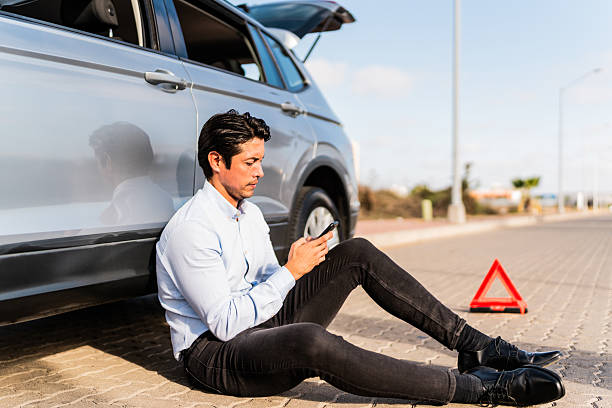 istock Mid adult man using mobile phone with car breakdown at road 2207831470