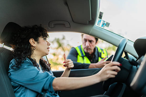 istock Young woman talking to traffic cop inside car 2207832723