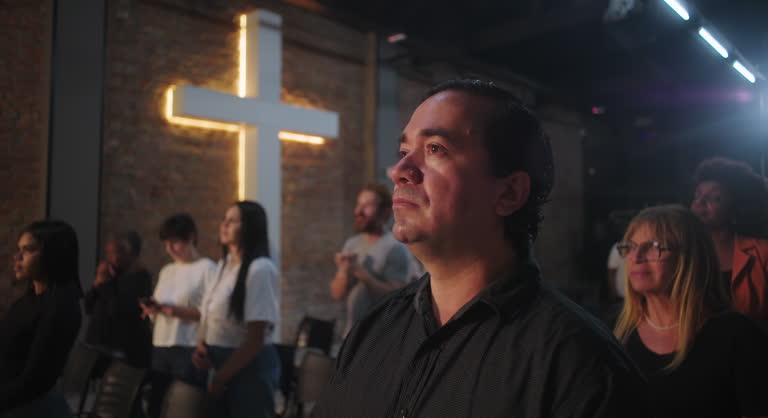 Close-up of a congregation member during a Christian event, standing in spiritual reflection with a glowing cross in the background